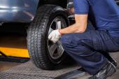Low section of mechanic fixing car tire at auto repair shop permutation pneus