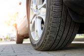 Car all-season tire close up, parked car. Low angle shot, wheel auto with aluminum rim concept usure-pneumatiques