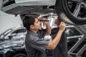 Asian mechanic Checking and torch tire in maintainance service center which is a part of showroom, technician or engineer professional work for customer, car repair concept usure-pneumatiques
